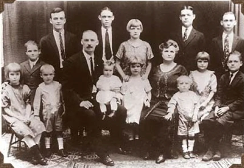 A formal sepia portrait of the O'Shevlin family, parents seated with eleven children